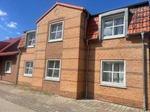 a brick building with four windows on a street at Pension Stral-Sund UG in Stralsund