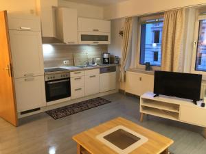 a kitchen with white cabinets and a tv and a table at Moderne Vollmöblierte Wohnung in Zwickau