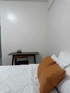 a bed with two pillows and a table in a room at Amani Grand Citygate in Pampanga