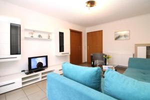 ein Wohnzimmer mit blauen Stühlen und einem Fernseher in der Unterkunft Ferienanlage Dröse, Haus 8a - Fewo 7 rolli-gerecht in Fulgen