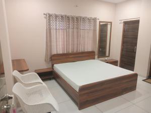 a bedroom with a bed and two chairs in it at Vaatsaly home's Rooms in Indore