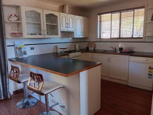 a kitchen with white cabinets and a black counter top at The Quiet Rose in Lithgow