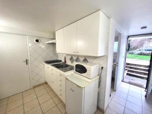 a small kitchen with white cabinets and a microwave at J1 St-Quentin-en -Yvelines Studio en Rez de jardin avec parking in Trappes +25 photos