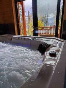 una vasca idromassaggio con acqua e una finestra di Dom drewniany z sauną i jacuzzi w Szklarskiej Porębie a Szklarska Poręba