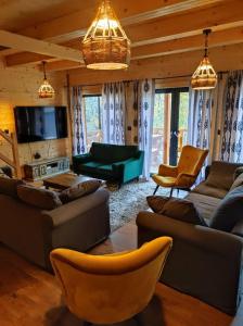 un soggiorno con divani, sedie e una TV di Dom drewniany z sauną i jacuzzi w Szklarskiej Porębie a Szklarska Poręba