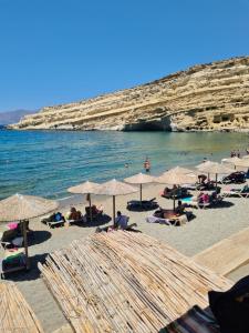 a group of people laying on a beach with umbrellas at Villa Iasmos in Pitsidia
