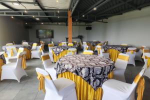 a room with tables and white chairs and a stage at Alinson Sunset Hill in Bogor +118 photos