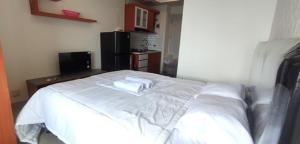 a white bed with two towels on top of it at Apartemen Grand Kamala Lagoon by JVT PRO in Pekayon Satu