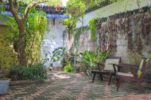 a patio with two benches and a tree at Lakmali Homestay in Watagederamulla