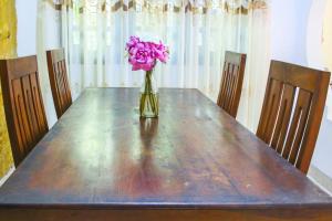 a vase of pink flowers sitting on a wooden table at Lakmali Homestay in Watagederamulla