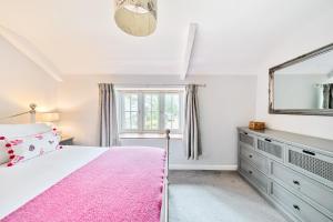 a bedroom with a pink bed and a mirror at Woodcutter's Cottage in Dorchester +24 photos