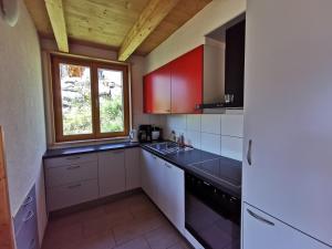 una cucina con armadi rossi e bianchi e una finestra di Chalet Mélèze in sonniger Lage mit schönem Ausblick , für 6 Personen a Mase