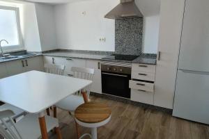 a kitchen with a white table and a white refrigerator at Casa Sáner in Rábade