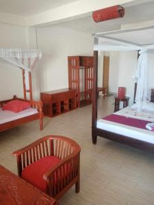 a room with three beds and a chair in it at villa Mena in Nosy Be
