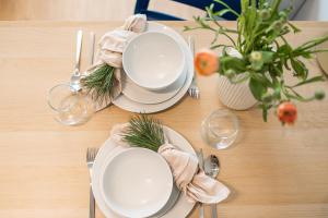 a table with white plates and silverware and a table set up with pine cones at Haga Home in Tallinn