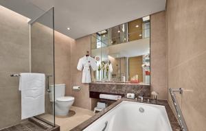 a bathroom with a tub and a toilet and a mirror at Shangri-La Tanjung Aru, Kota Kinabalu in Kota Kinabalu
