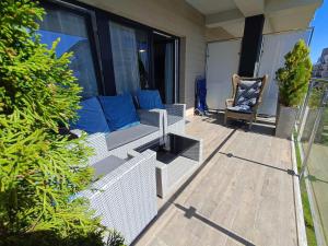 a porch with a couch and a chair at Apartamenty Relaks & Spa Pięć Mórz in Sianozety