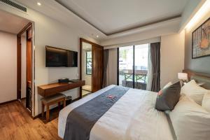 a bedroom with a bed and a desk and a television at Edoya Hotel Ben Thanh in Ho Chi Minh City