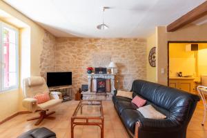 sala de estar con sofá de cuero y chimenea en Escale des Crozes, en Saint-Romain-en-Viennois