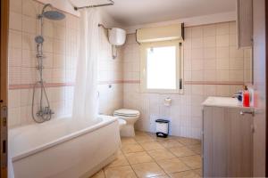 a bathroom with a tub and a toilet and a window at Sestu house via monserrato rooms in Sestu +14 photos