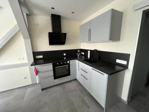 a kitchen with white cabinets and a black counter top at Ferienwohnung Lange in Kalbe +3 photos