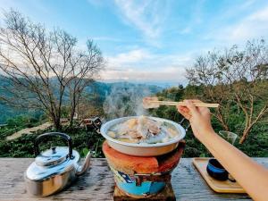 a person is eating a bowl of food with chopsticks at Ma Family Coffee Farm ไร่กาแฟครอบครัวมะ in Ban Huai Pong Nam Ron +57 photos