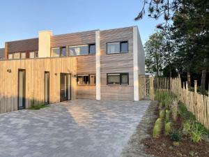 a wooden house with a driveway in front of it at Welcome in - Groepsaccommodatie Lepelblad 42 en 44 Nieuwvliet-Bad in Nieuwvliet-Bad