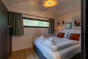 a large white bed in a room with a window at Welcome in - Tinyhouse La Mouette met zonnig terras, Zoutelande in Zoutelande