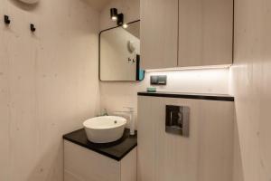 a white bathroom with a sink and a mirror at Welcome in - Tinyhouse La Mouette met zonnig terras, Zoutelande in Zoutelande +25 photos