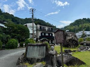 a statue of a person standing next to a sign at 宿坊かつら in Izu