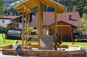 a young girl is standing in a wooden play structure at Haus Fuchs in Haus im Ennstal