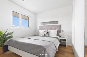 a white bedroom with a large bed and two windows at Ferienwohnung Harbour Side, App 7 Olpenitz in Olpenitz