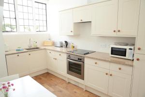 a white kitchen with white cabinets and a microwave at Divine in Georgeham