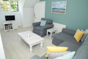 a living room with a couch and chairs and a tv at Divine in Georgeham