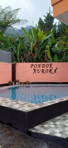 a swimming pool with a sign on a wall at Villa Pondok Aurora in Campaka