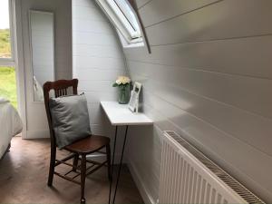 a chair sitting next to a table in a room at Sandy Meadow Escapes in Lairg