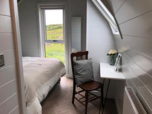 a bedroom with a bed and a desk and a window at Sandy Meadow Escapes in Lairg