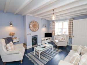 a living room with white furniture and a fireplace at Adventure Cottage in Whitby