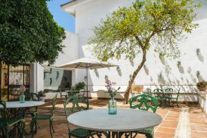 Un patio con mesas y sillas y un árbol. en Crisol Jardines de Córdoba, en Córdoba