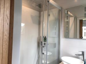 a bathroom with a glass shower and a sink at Sandy Meadow Escapes in Lairg