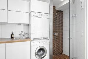 a kitchen with a washing machine and a sink at 7 min to Ski Championship, Glass front house, Terrace in Trondheim