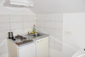 a white tiled kitchen with a sink and a stove at Apartments Park Vodice - Ljubljana, Krvavec in Woditz