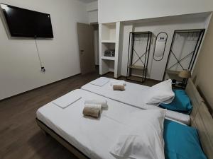 Aegina Downtown Apartments 1 في ايجينا تاون: غرفة نوم بها سريرين وتلفزيون بشاشة مسطحة