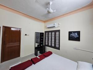 a bedroom with a bed and a door and a television at Shriya Home Stay in Madurai +29 photos