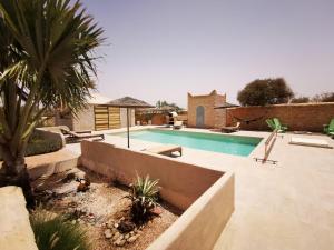 a swimming pool with a palm tree and a house at Villa Douira avec piscine, proche d'Essaouira in Essaouira