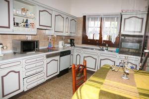 a kitchen with white cabinets and a table and a microwave at Cosy Villa in Pikérmion