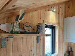 a kitchen shelf with utensils on a wooden wall at Sandy Meadow Escapes in Lairg
