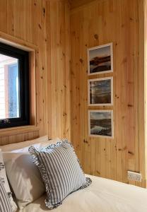 a bedroom with wooden walls and a bed with a pillow at Sandy Meadow Escapes in Lairg