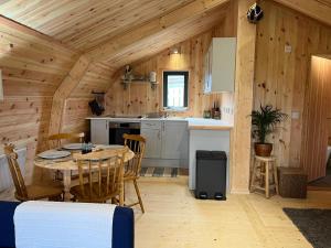 a kitchen with a table and chairs in a cabin at Sandy Meadow Escapes in Lairg