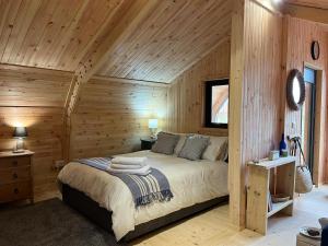 a bedroom with a bed in a wooden wall at Sandy Meadow Escapes in Lairg